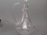 un pichet en verre transparent posé sur une table à côté d'un vase violet