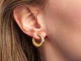 a close up of a woman wearing a pair of gold hoop earrings