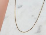un collier à chaîne en or posé sur une surface en marbre