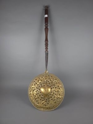 une cloche ancienne en laiton avec une poignée en bois sur fond gris