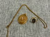 un gros plan d'un collier en or avec une chaîne posé sur un tissu gris