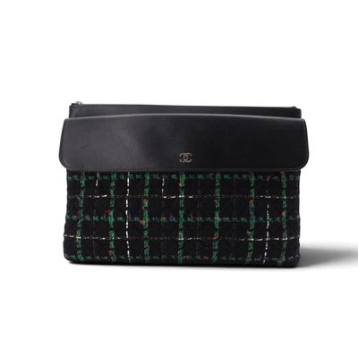un sac à main à carreaux noirs et verts, muni d'une poignée en cuir noir