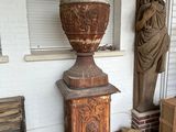 un grand vase posé sur un socle à côté d'une statue