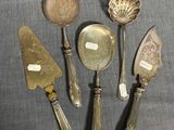 cinq cuillères en métal argenté et un couteau posés sur une table
