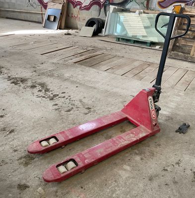 un scooter rouge posé par terre devant un mur recouvert de graffitis