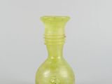 a small yellow glass vase sitting on a white surface