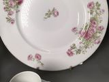 a white plate with pink flowers on it next to a cup and saucer