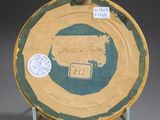 a yellow and green plate on a stand with a sticker on it