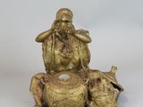 a gold statue of a man sitting on top of a dog