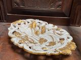 an ornate gold and white plate sitting on top of a wooden table