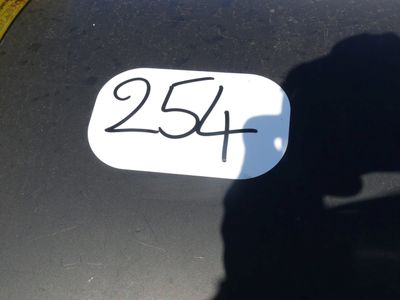 l'ombre d'une personne tenant un téléphone portable devant une plaque d'immatriculation