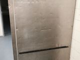 a metal refrigerator that is in the corner of a room