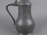 un pichet ancien en pewter muni d'une anse, sur fond gris