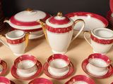 a lot of red and white dishes and cups on the table