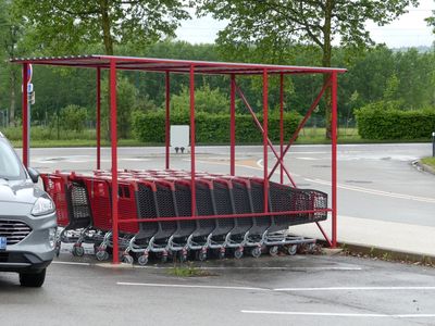 des voitures garées sur un parking, avec un caddie au milieu de celui-ci
