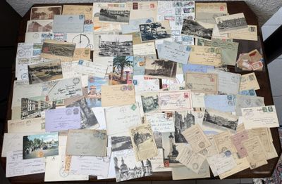 de nombreuses cartes postales anciennes posées sur une table, avec une chaise en arrière-plan