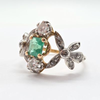 gros plan d'une bague avec une pierre verte entourée de diamants
