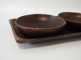 two wooden bowls on a tray on a white table
