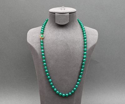 un collier de perles vertes sur un mannequin, muni d'un fermoir doré