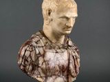an antique marble bust of a man with a chain around his neck