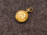 une image représentant une montre de poche en or posée sur une surface grise