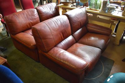 a brown leather couch sitting in a room with other furniture in the background