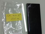 un téléphone portable noir à côté d'un autocollant jaune sur un mur blanc