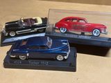 trois petites voitures dans une vitrine posée sur une table