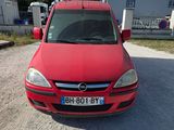 La voiture rouge est garée sur la terre battue du parking.