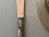 a silver plate with a knife on it next to a silver plate with a knife on it