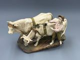 a figurine of a man on a horse pulling a plow