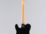 a black electric guitar hanging from a white wall