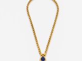 a gold necklace with a blue stone pendant on a chain