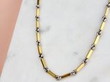 un gros plan d'un collier en or et en argent posé sur une surface en marbre