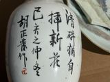 a white vase with asian writing on it next to a plate