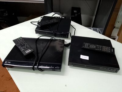 three laptops sitting on a table with remotes on them