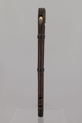 an old wooden flute with a black handle on a clear surface