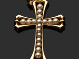 un pendentif en forme de croix, en or et perles, sur fond noir