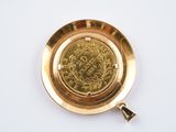 a gold plate with a coin in it on a white surface