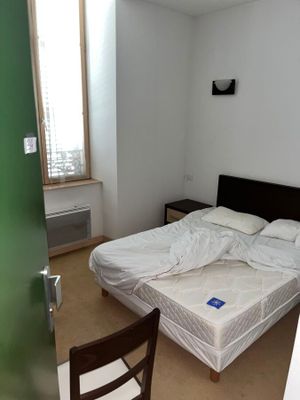 un lit dans une chambre avec une chaise et une fenêtre