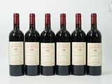 six bouteilles de vin rouge alignées sur une surface blanche
