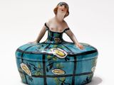 une figurine représentant une femme assise sur une boîte