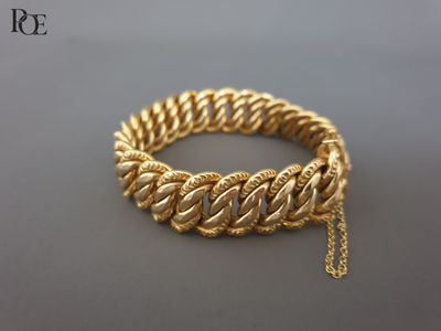 gros plan d'un bracelet en or avec une chaîne