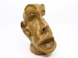 une sculpture représentant le visage d'un homme sur une surface blanche