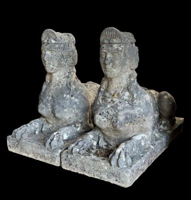 une paire de statues en pierre représentant un homme et une femme assis sur un bloc de pierre