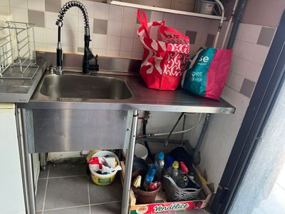 un évier dans un coin de la cuisine, avec un panier posé sur le plan de travail