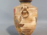 a vase that has a bird on it on a gray surface