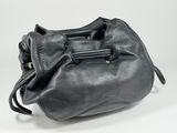 the black leather bag is sitting on a white surface