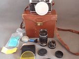 un étui marron contenant un appareil photo, un objectif et d'autres accessoires