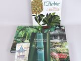 three books on a white table with a plant in the background